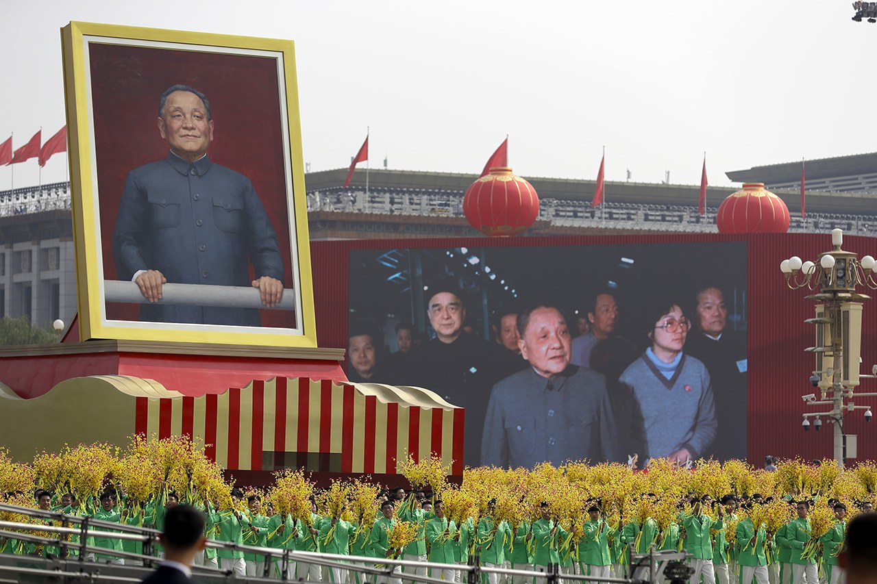 2019年10月1日，中共建政70周年庆典上，持花的游行队伍环绕巨型的邓小平画像。（美联社资料图片）