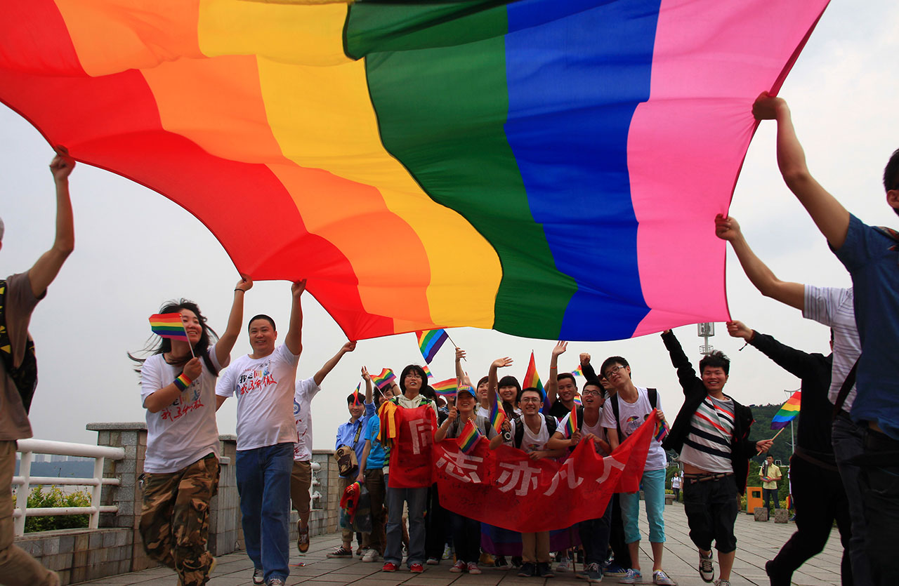 2013年5月17日，湖南长沙举行的国际反恐同日游行，活动人士高举彩虹旗，横幅上写着“同志亦凡人”。（路透社）