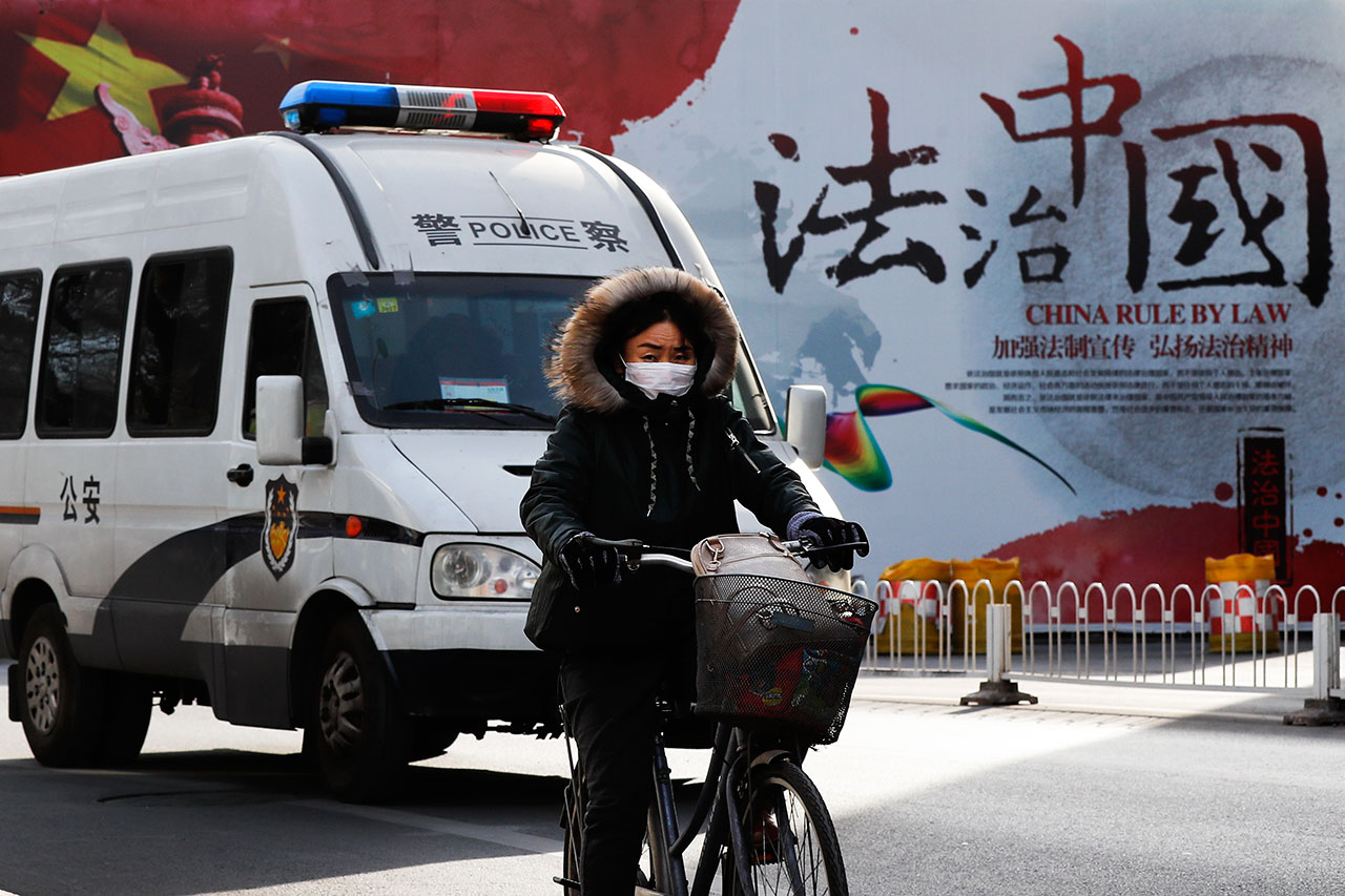 一辆警车驶过北京街头的中国法治宣传墙（美联社）